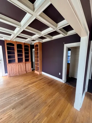 a view of an empty room with wooden floor and a ceiling fan