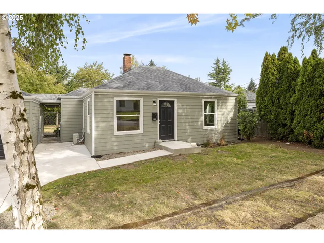 a view of a yard in front of a house with a large tree