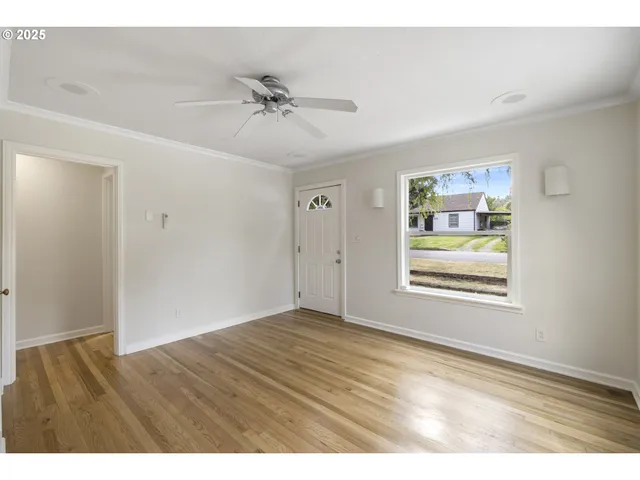 a view of an empty room with wooden floor and a window