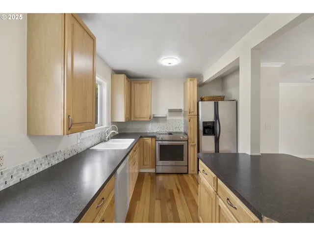 a kitchen with stainless steel appliances granite countertop a sink a stove and a refrigerator