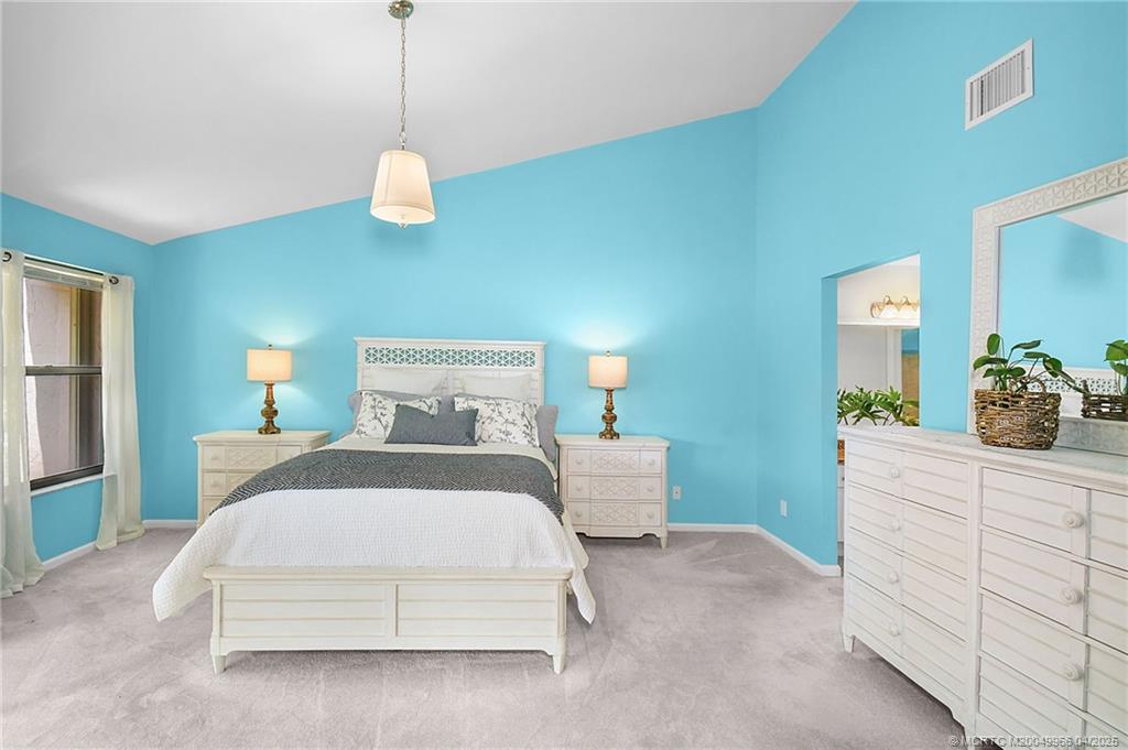 3401 Southeast Martinique Trace, Unit 101 Stuart, FL 34997 - Photo 25 of 51 a bedroom with a large bed and a chandelier