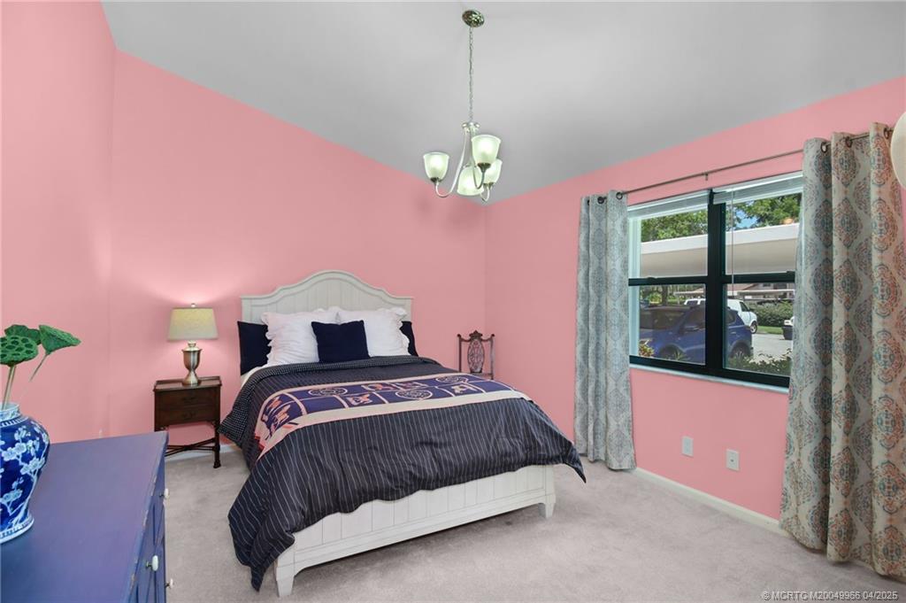 3401 Southeast Martinique Trace, Unit 101 Stuart, FL 34997 - Photo 32 of 51 a bedroom with a bed chandelier and a window