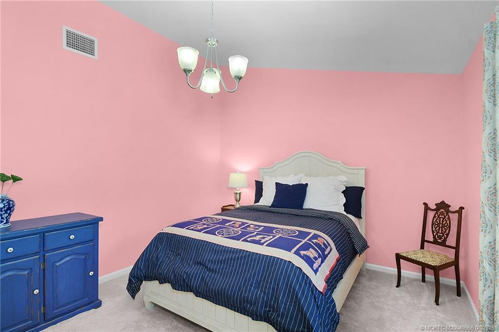 3401 Southeast Martinique Trace, Unit 101 Stuart, FL 34997 - Photo 33 of 51 a bedroom with a bed and a chandelier