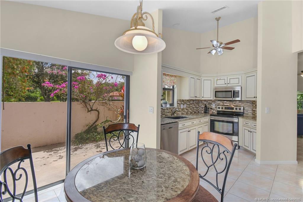 3401 Southeast Martinique Trace, Unit 101 Stuart, FL 34997 - Photo 39 of 51 a kitchen with stainless steel appliances granite countertop a stove top oven a kitchen island a dining table and chairs