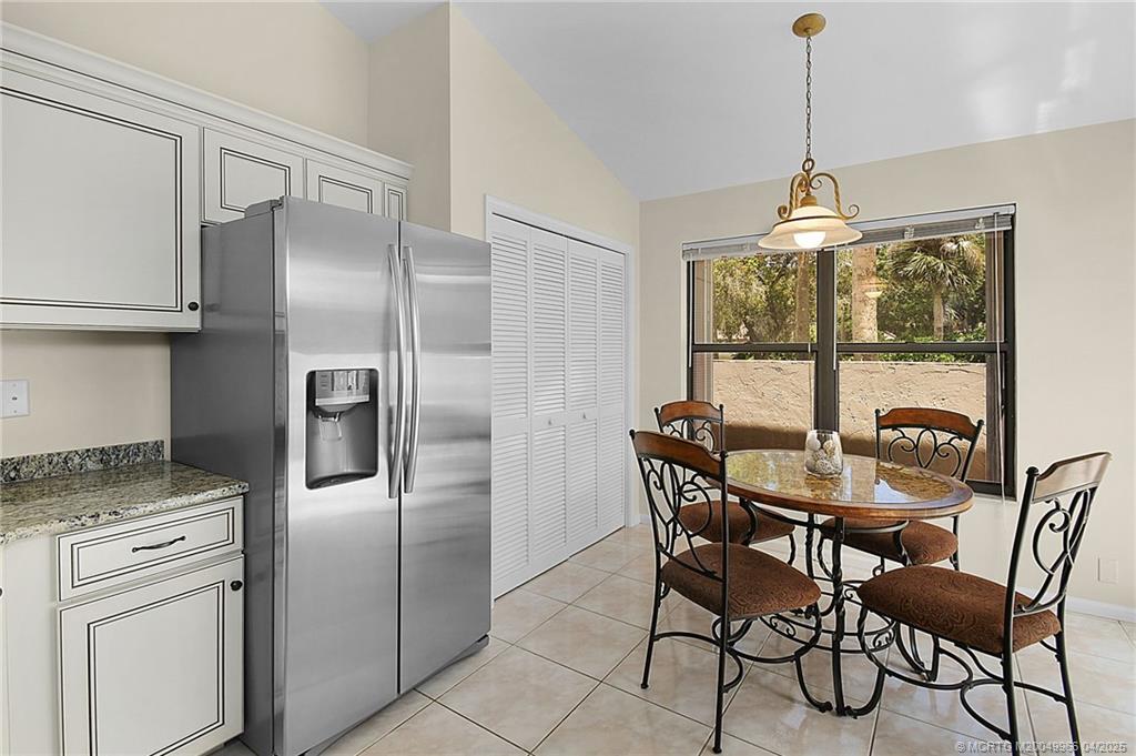 3401 Southeast Martinique Trace, Unit 101 Stuart, FL 34997 - Photo 41 of 51 a kitchen with stainless steel appliances granite countertop a refrigerator a stove a dining table and chairs with wooden floor
