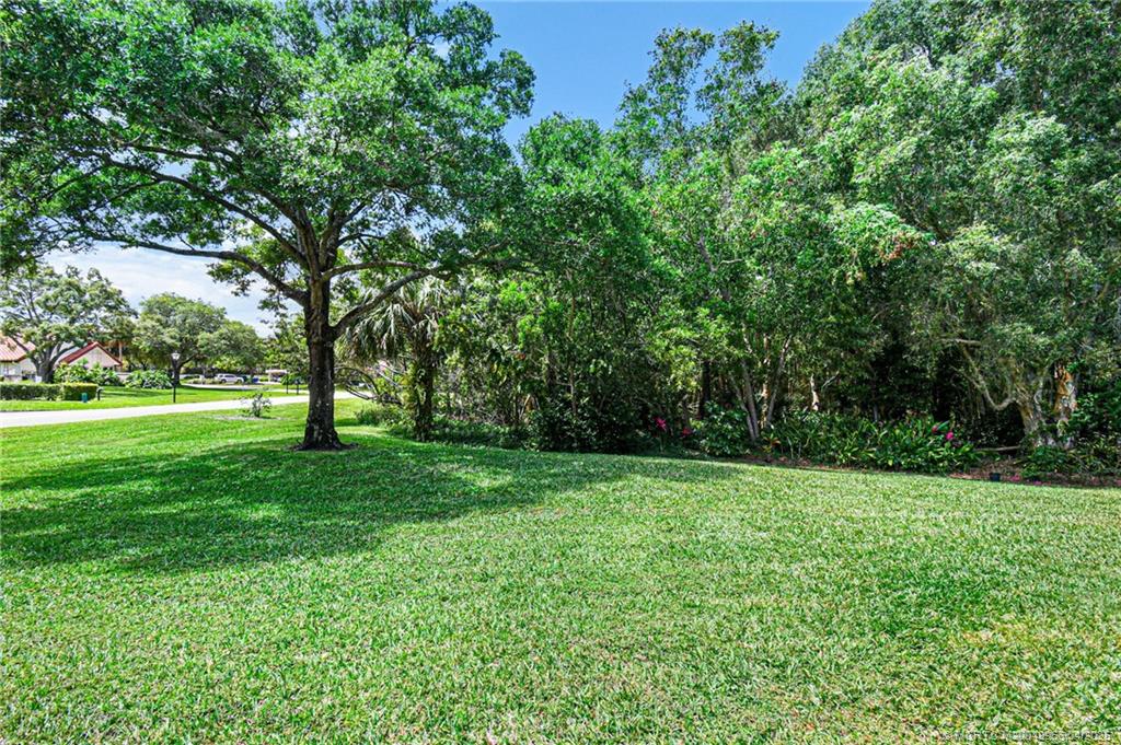 3401 Southeast Martinique Trace, Unit 101 Stuart, FL 34997 - Photo 7 of 51 a view of a grassy field with trees in the background