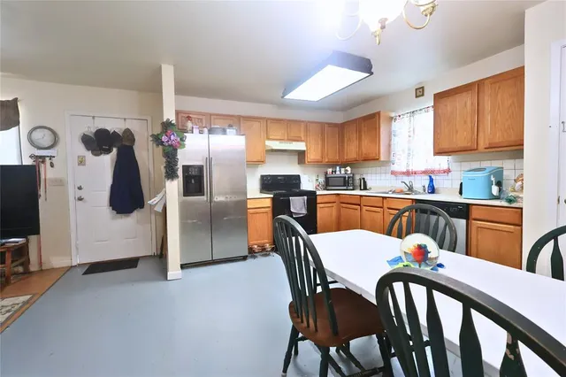 a kitchen with stainless steel appliances a dining table chairs and a refrigerator