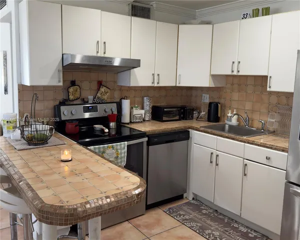 a kitchen with stainless steel appliances granite countertop a sink a stove a refrigerator and cabinets