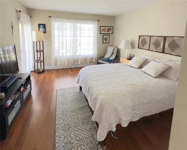 a bedroom with a bed rug and wooden floor