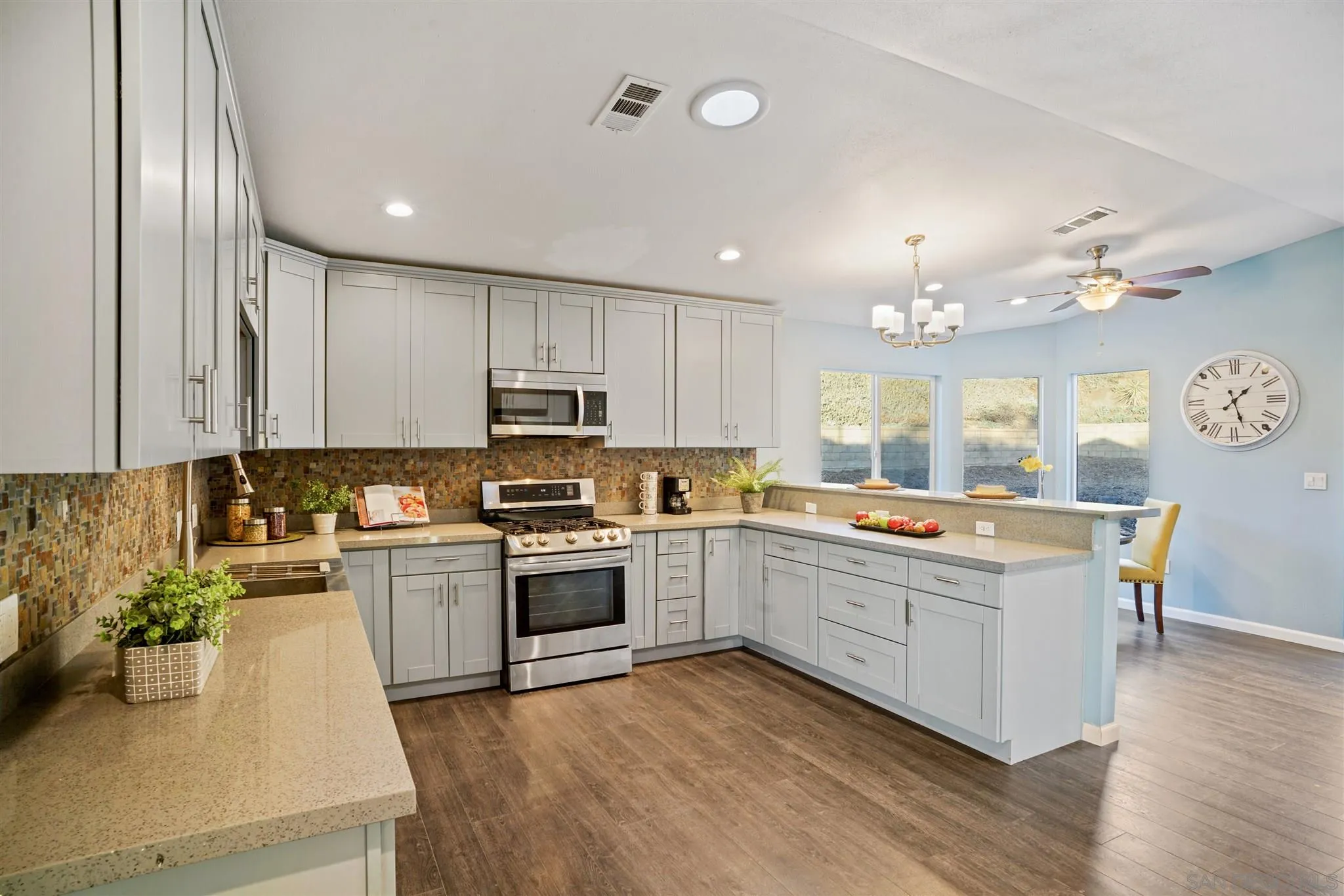 a large kitchen with kitchen island a stove a sink a refrigerator dining table and chairs with wooden floor