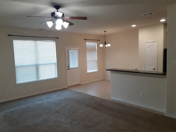an empty room with chandelier fan and windows