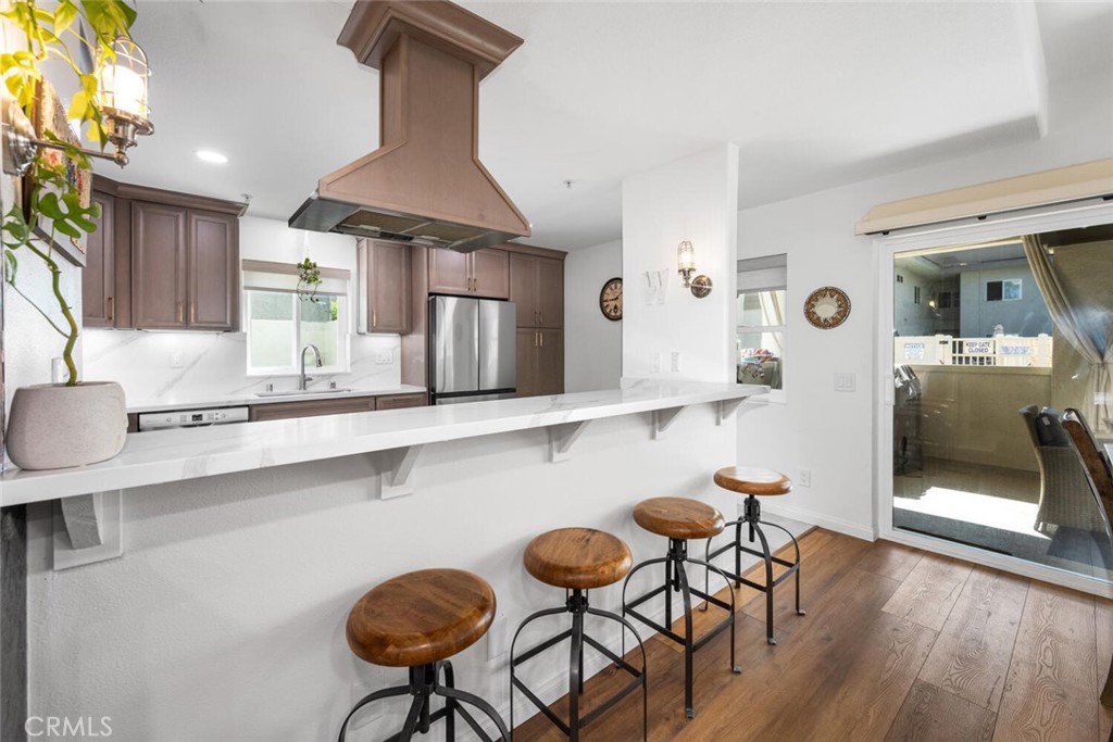 1516 Pacific Coast Highway, Unit 101 Huntington Beach, CA 92648 - Photo 10 of 58 a kitchen with stainless steel appliances a dining table chairs and a refrigerator a sink with wooden floor