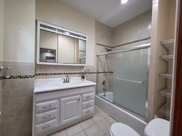 a bathroom with a granite countertop sink toilet mirror vanity and shower