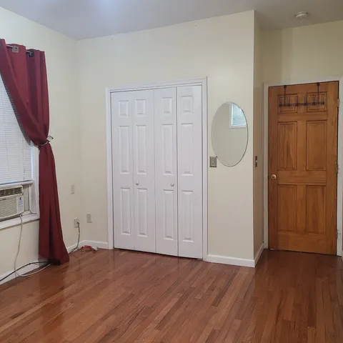 an empty room with wooden floor and a cabinet