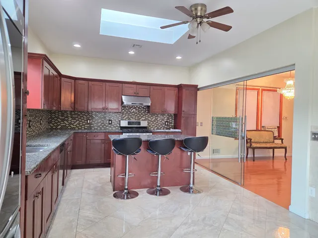 a kitchen with kitchen island granite countertop a table chairs sink and cabinets