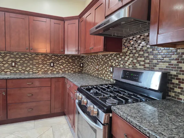 a kitchen with granite countertop stainless steel appliances stove and cabinets
