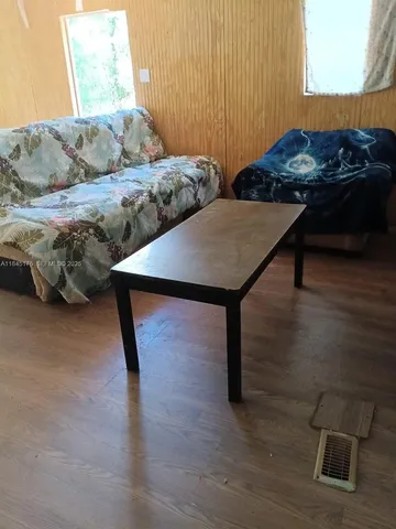 a living room with couches and kitchen view with wooden floor