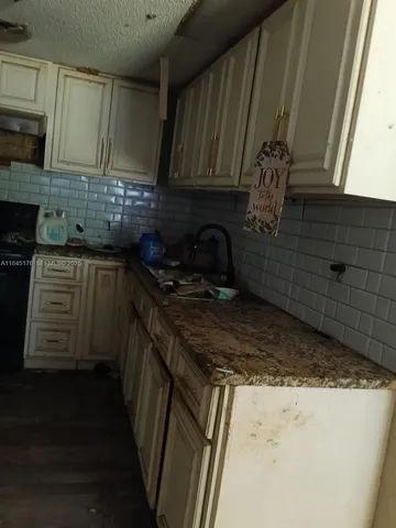 a kitchen with granite countertop a sink stove and cabinets