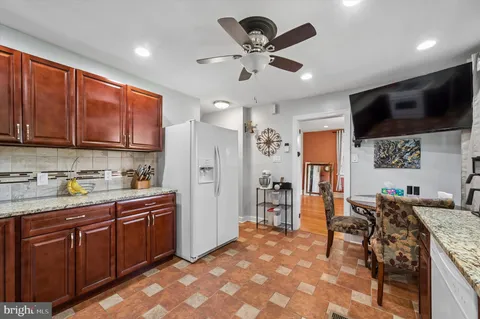 a kitchen with stainless steel appliances granite countertop a refrigerator a sink dishwasher a stove with wooden cabinets and floor