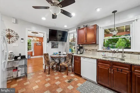 a open kitchen with stainless steel appliances granite countertop a sink dishwasher a dining table and chairs with wooden floor