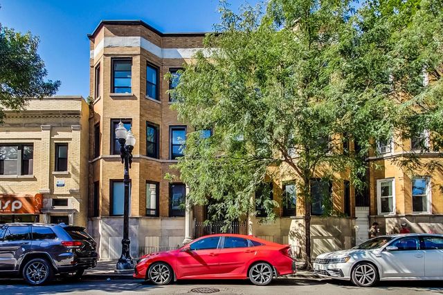 a front view of a building with cars parked