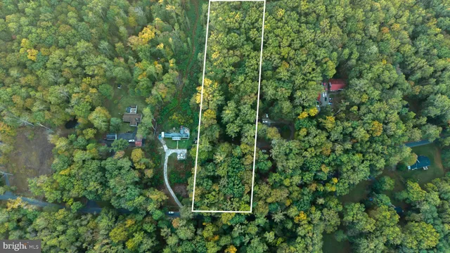 an aerial view of residential house with outdoor space and trees all around