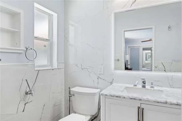 a bathroom with a granite countertop sink a toilet and a mirror