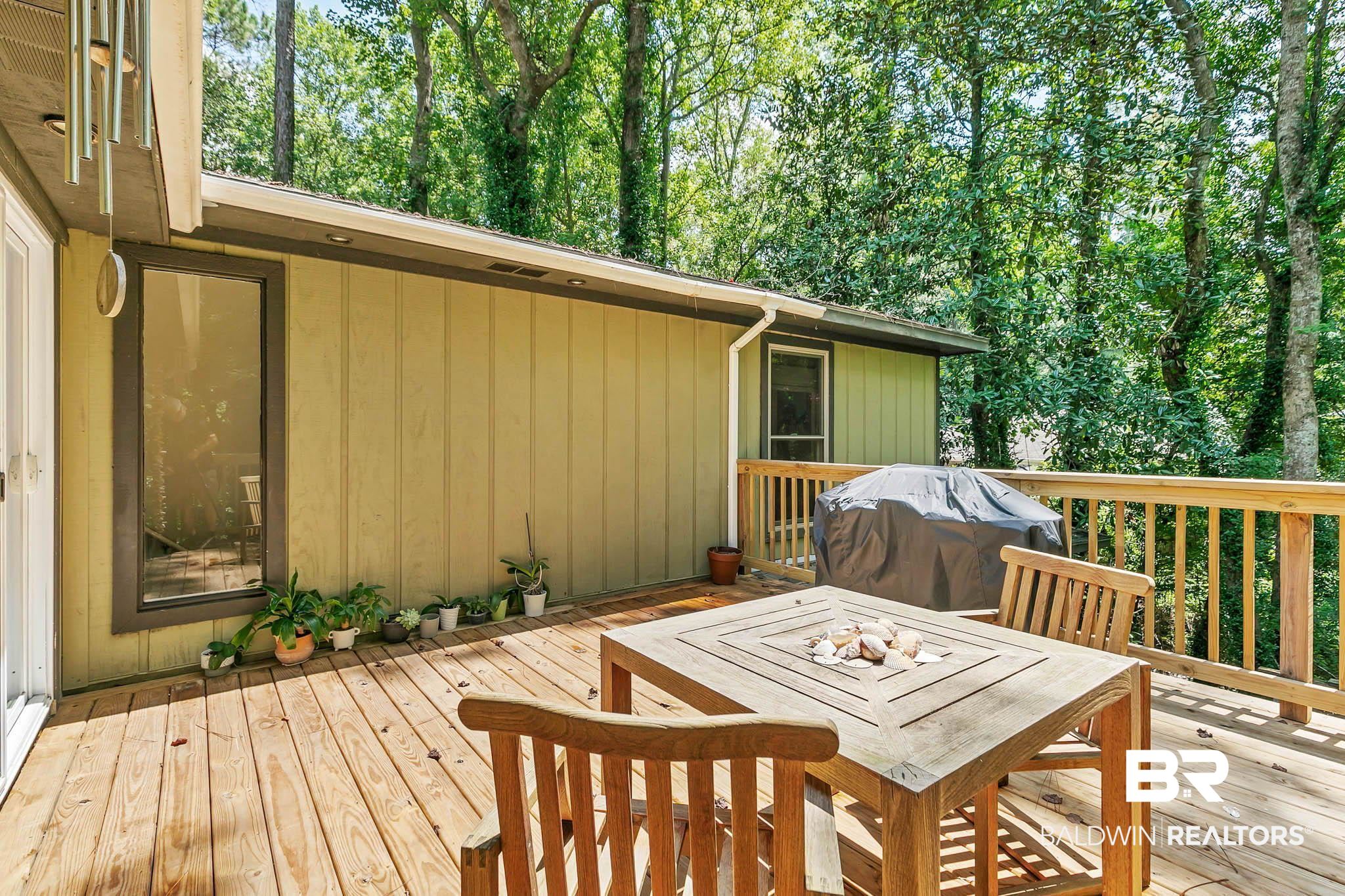 332 Ridgewood Drive Daphne, AL 36526 - Photo 27 of 48 Deck with outdoor dining area, grilling area, and view of scattered trees
