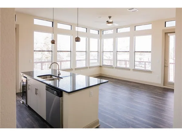 a kitchen with stainless steel appliances granite countertop a sink a stove and a wooden floors
