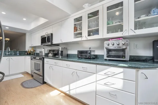 a kitchen with granite countertop a stove a sink and a microwave