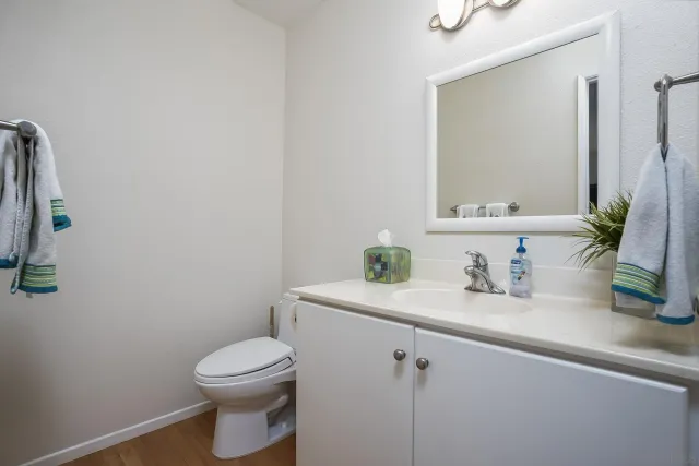 a bathroom with a granite countertop sink a toilet and mirror