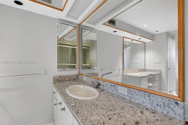 a bathroom with a granite countertop sink and a mirror