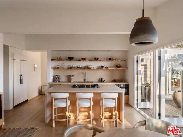 a kitchen with stainless steel appliances granite countertop a stove a chimney a dining table and chairs