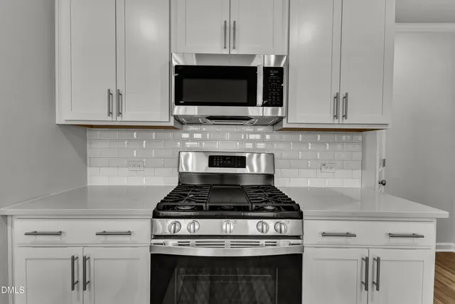 a kitchen with stainless steel appliances granite countertop white cabinets stove top oven and microwave