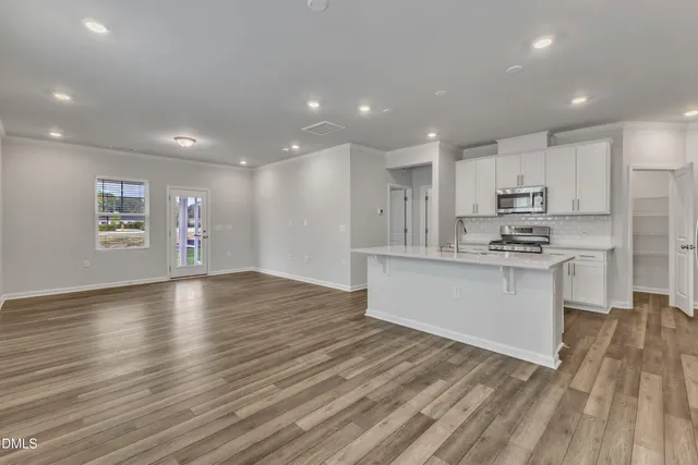 a kitchen with stainless steel appliances granite countertop a stove top oven a sink dishwasher and a refrigerator with wooden floor