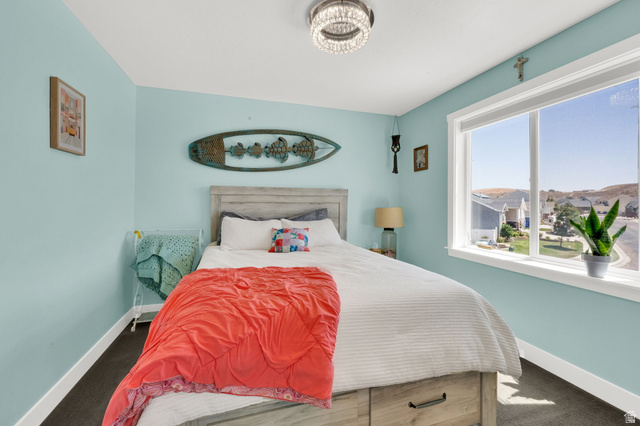 1857 Thunder Gulch Road Eagle Mountain, UT 84005 - Photo 28 of 50 Bedroom featuring light blue walls, dark carpet flooring, and a large window with white trim