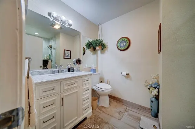 a bathroom with a granite countertop toilet a sink and a mirror