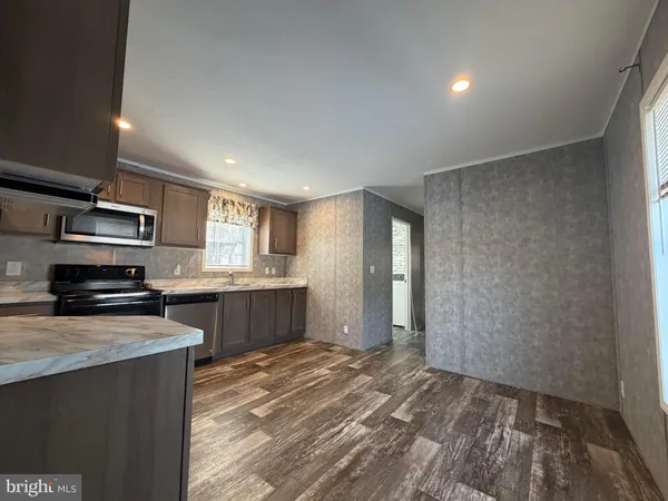 a large kitchen with a sink and dishwasher a stove top oven with wooden floor