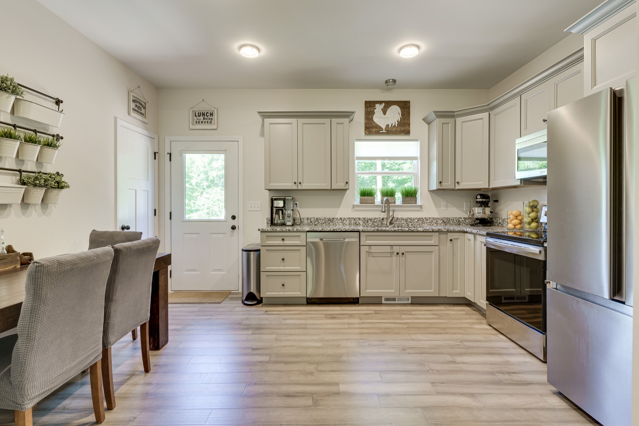 1170 Cowan Road Dickson, TN 37055 - Photo 10 of 30 a kitchen with stainless steel appliances white cabinets a wooden floor and a window