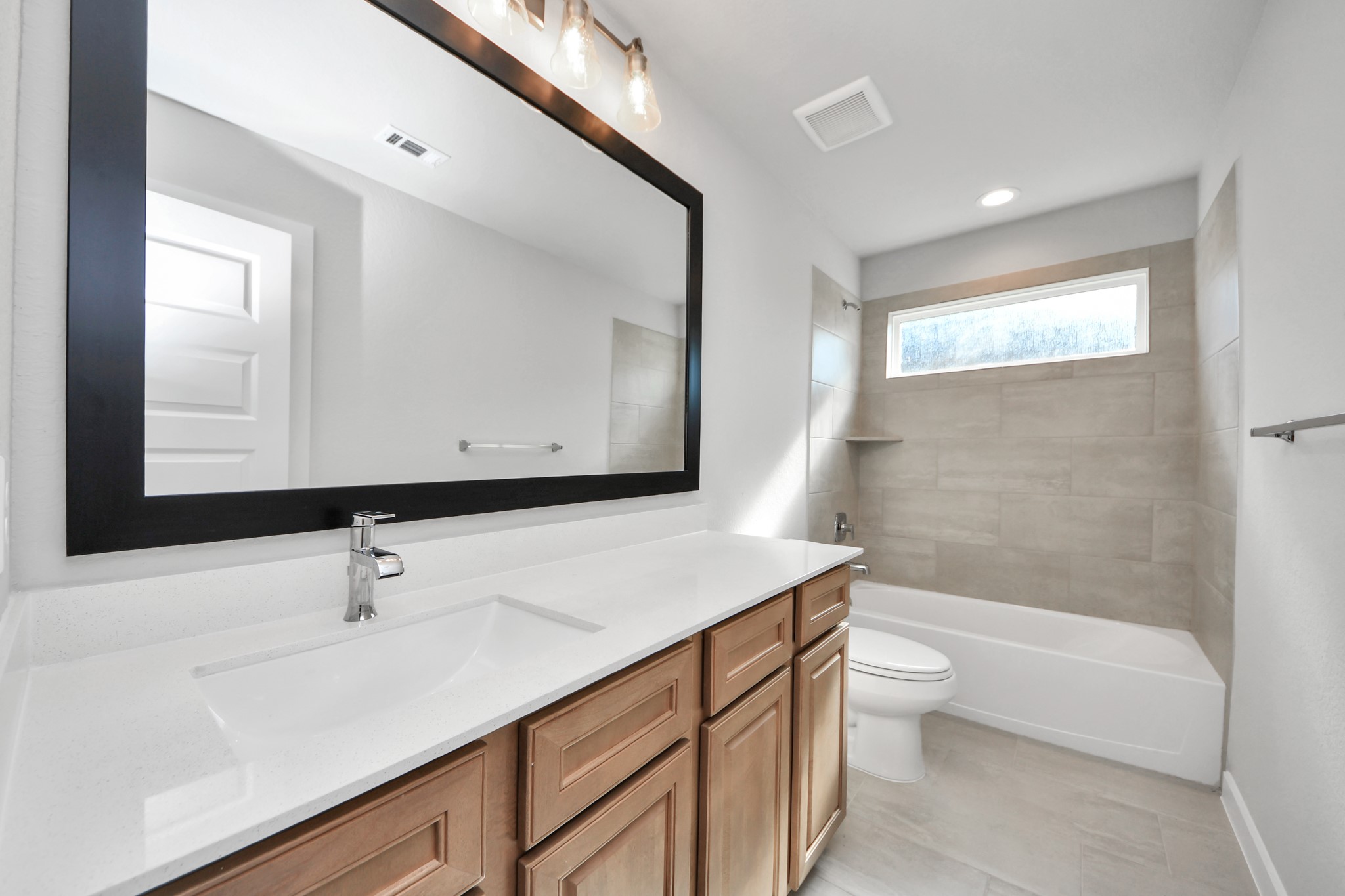 3102 Native Spg Drive Spring, TX 77373 - Photo 36 of 40 Secondary bath features tile flooring, bath/shower combo with tile surround, light stained wood cabinets, beautiful light countertop. Sample photo of completed home with similar floor plan. Actual colors and selections may vary.