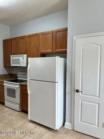 a white refrigerator freezer and a stove sitting inside of a kitchen