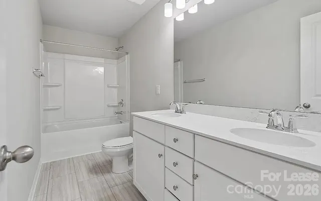 a bathroom with a double vanity sink toilet mirror and shower