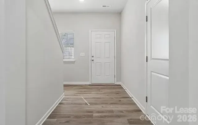 a view of a hallway with wooden floor and a bathroom