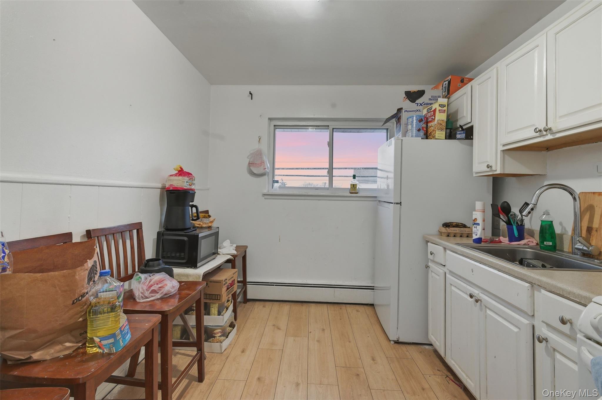 90 Conklin Avenue Haverstraw, NY 10927 - Photo 3 of 17 Kitchen with white cabinets, light countertops, floors, a baseboard heating unit, and freestanding refrigerator