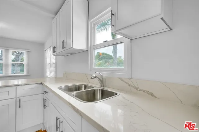 a kitchen with white cabinets a sink and a window