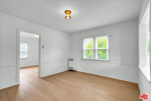 an empty room with a window and wooden floor