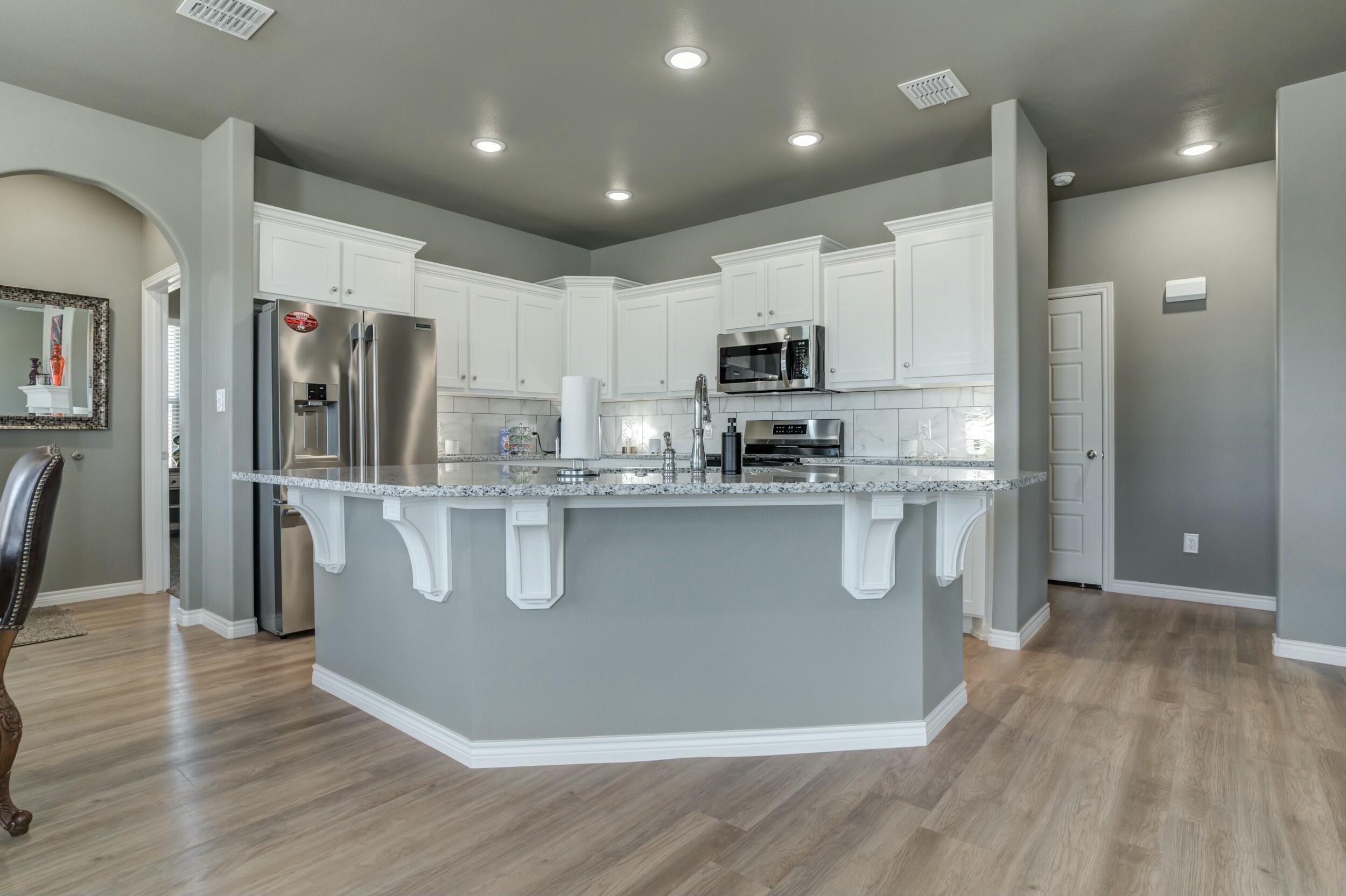 6928 11th Street Lubbock, TX 79416 - Photo 16 of 42 a kitchen with stainless steel appliances granite countertop a refrigerator a stove a sink a washer and dryer with wooden floors