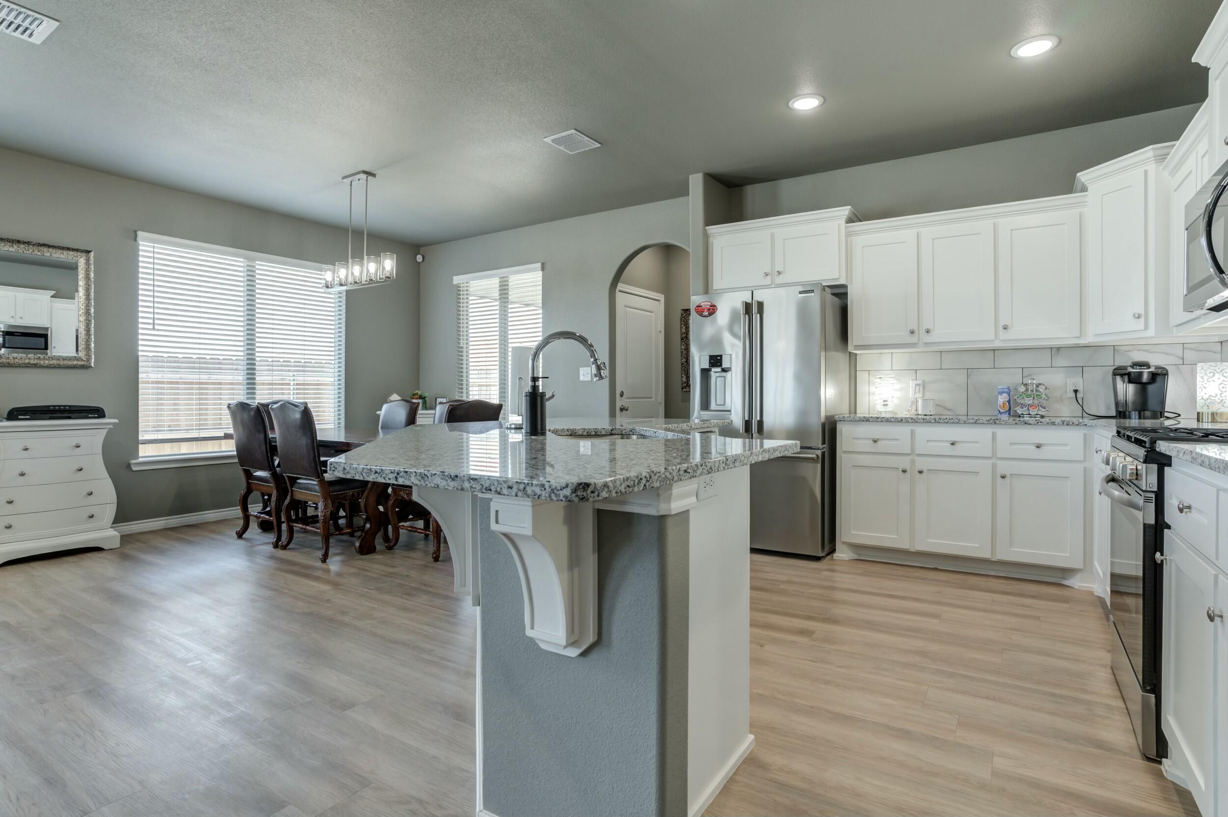 6928 11th Street Lubbock, TX 79416 - Photo 17 of 42 a kitchen with kitchen island granite countertop a sink cabinets and wooden floor