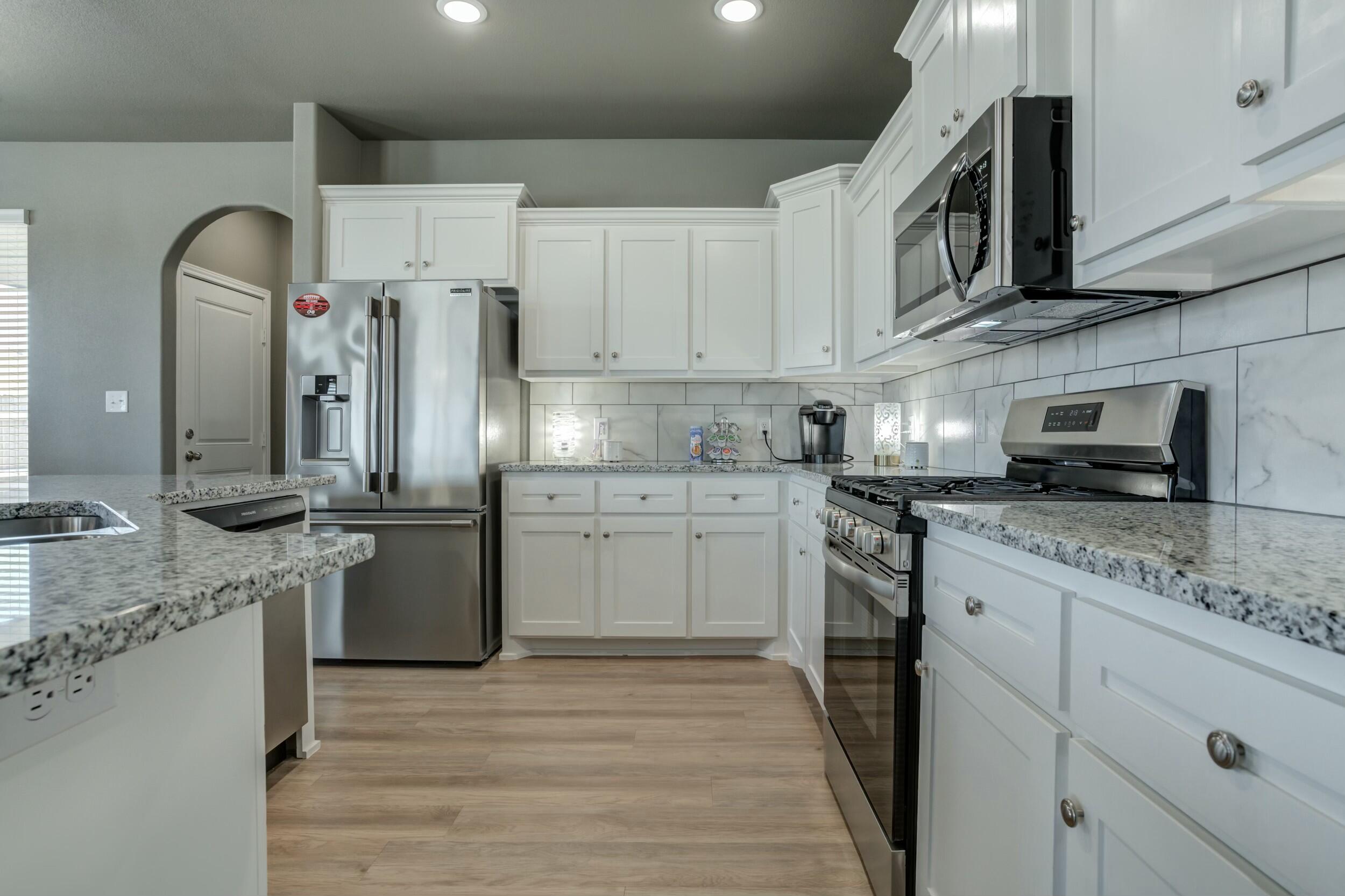 6928 11th Street Lubbock, TX 79416 - Photo 18 of 42 a kitchen with stainless steel appliances granite countertop a sink a stove a refrigerator and cabinets