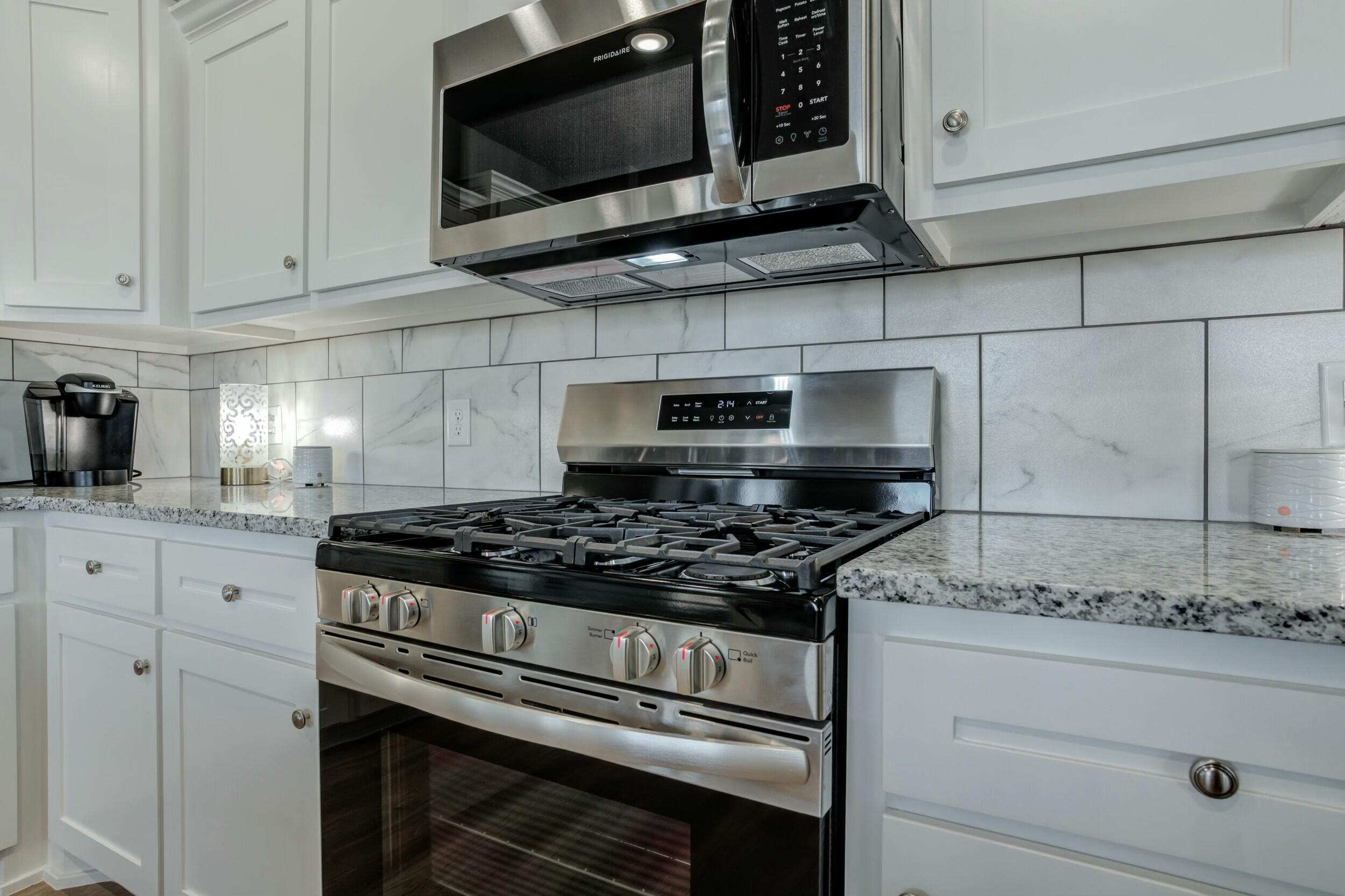 6928 11th Street Lubbock, TX 79416 - Photo 19 of 42 a kitchen with granite countertop white cabinets stainless steel appliances and a sink